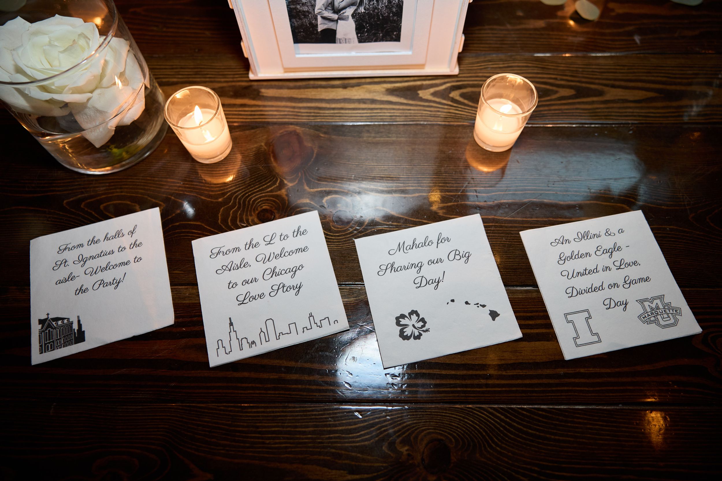 Place cards and glowing candles line a wooden surface creating an intimate dining atmosphere.
