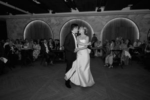 Wedding reception dance floor scene with guests dancing in a dimly lit ballroom.