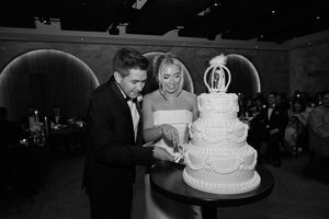 A white tiered wedding cake with floral decorations sits on display at a reception.