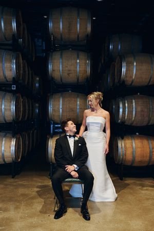 Couple sitting together in a wine cellar with rustic wooden barrels creating a romantic atmosphere.