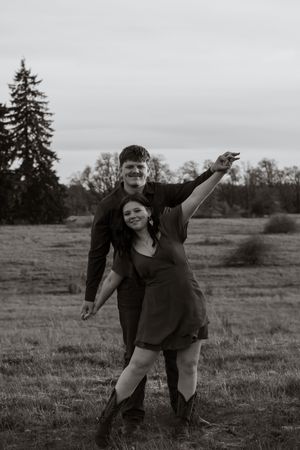 A black and white photo of a couple dancing and laughing together in an open field in rochester washington taken by washington photographer