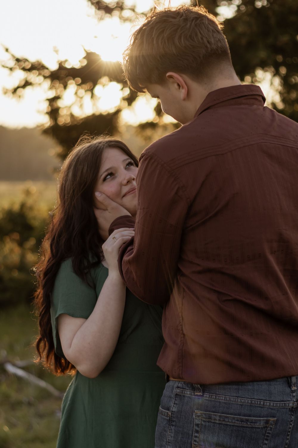 Woman in green dress gazes lovingly at her partner during a warm sunset photo session in rochester washington with olympia photographer