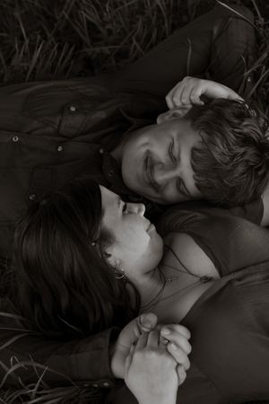 Intimate black and white photo of couple lying in grass, holding hands and gazing at each other in rochester taken by olympia photographer