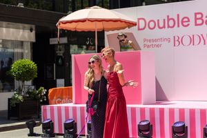 A pink-themed outdoor event setup with umbrellas and display stands against a dark background.