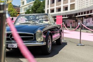 Vintage black sports car with sleek design and chrome accents parked on a city street.