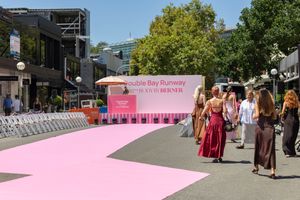 A pink-colored walkway or plaza area with people walking through an urban setting on a sunny day.
