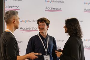 Three people having an animated discussion at a Google for Startups Accelerator event.