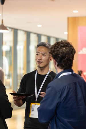 Two professionals engaged in conversation during a business networking event in a bright hallway.