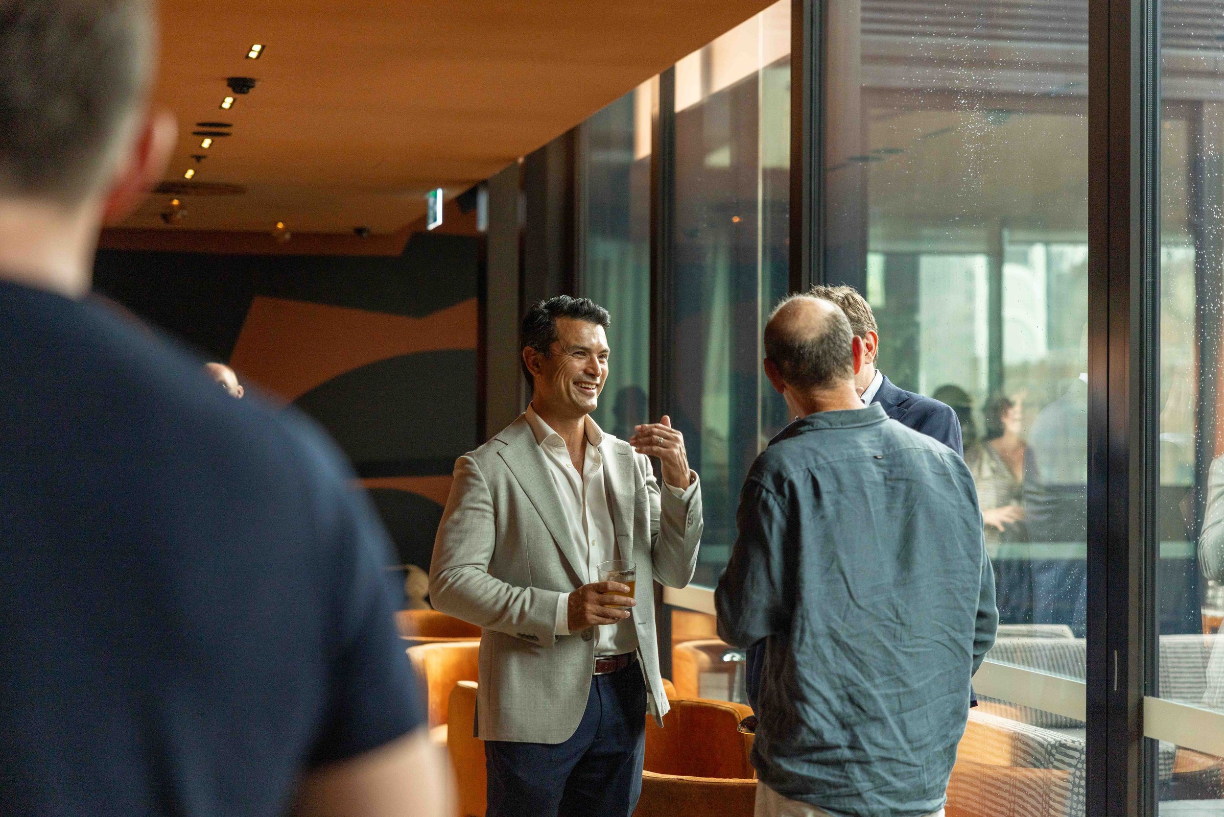 Two people having a conversation in a modern office space with glass walls and warm lighting.