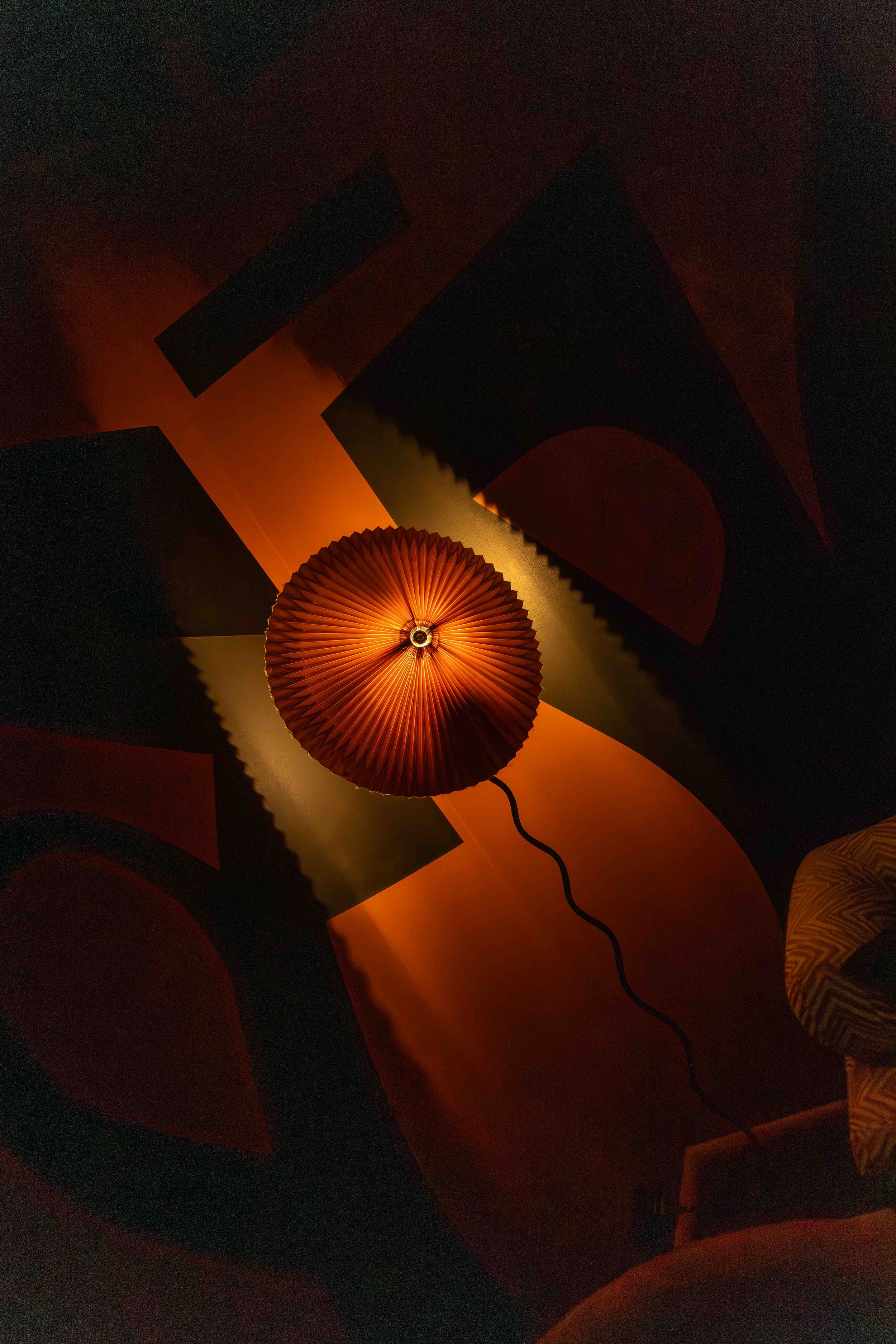 Orange paper lantern lights create a warm ambient glow against a dark ceiling in an artistic arrangement.