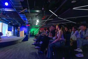 Nightclub interior with blue and green lighting illuminating a dark space filled with people watching a performance.