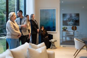 People gathered in a modern gallery space viewing artwork and socializing during an exhibition opening.