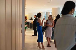 People mingling at a social gathering in a modern indoor space with bright lighting.