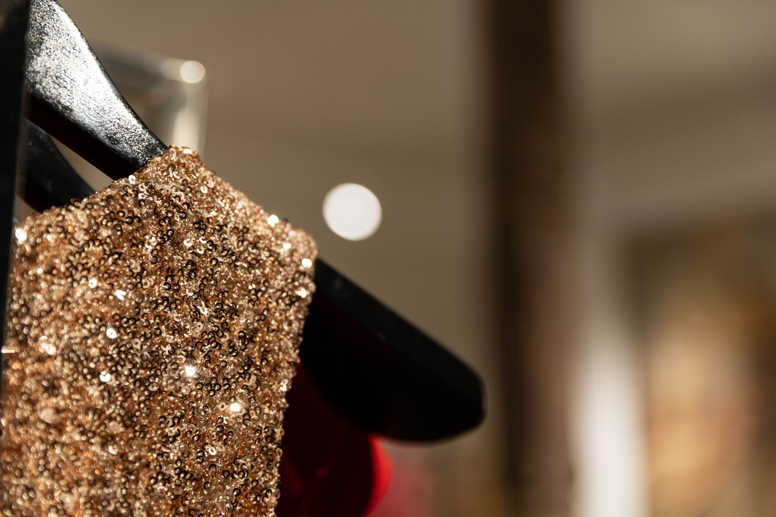 A row of sparkling gold sequined dresses hanging on a clothing rack in a retail store.