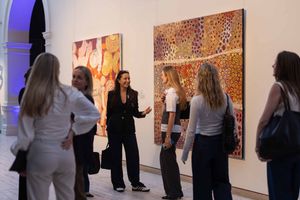 Gallery visitors view artwork displayed on white walls in a contemporary art exhibition space.
