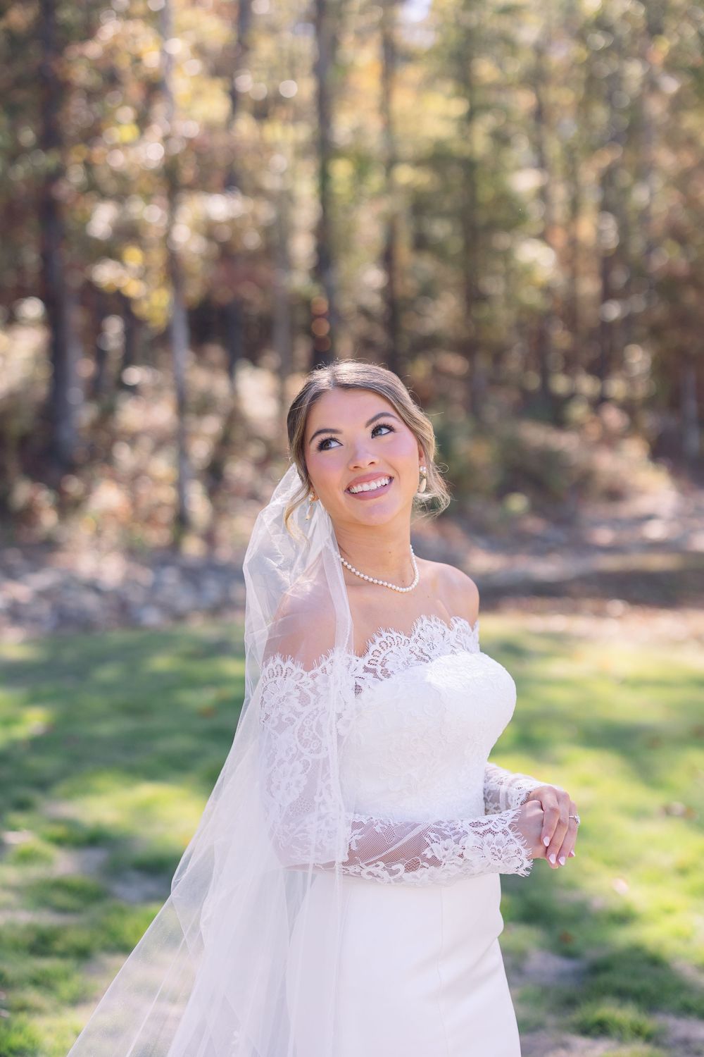 Bride in lace wedding dress twirls joyfully in an outdoor autumn setting.