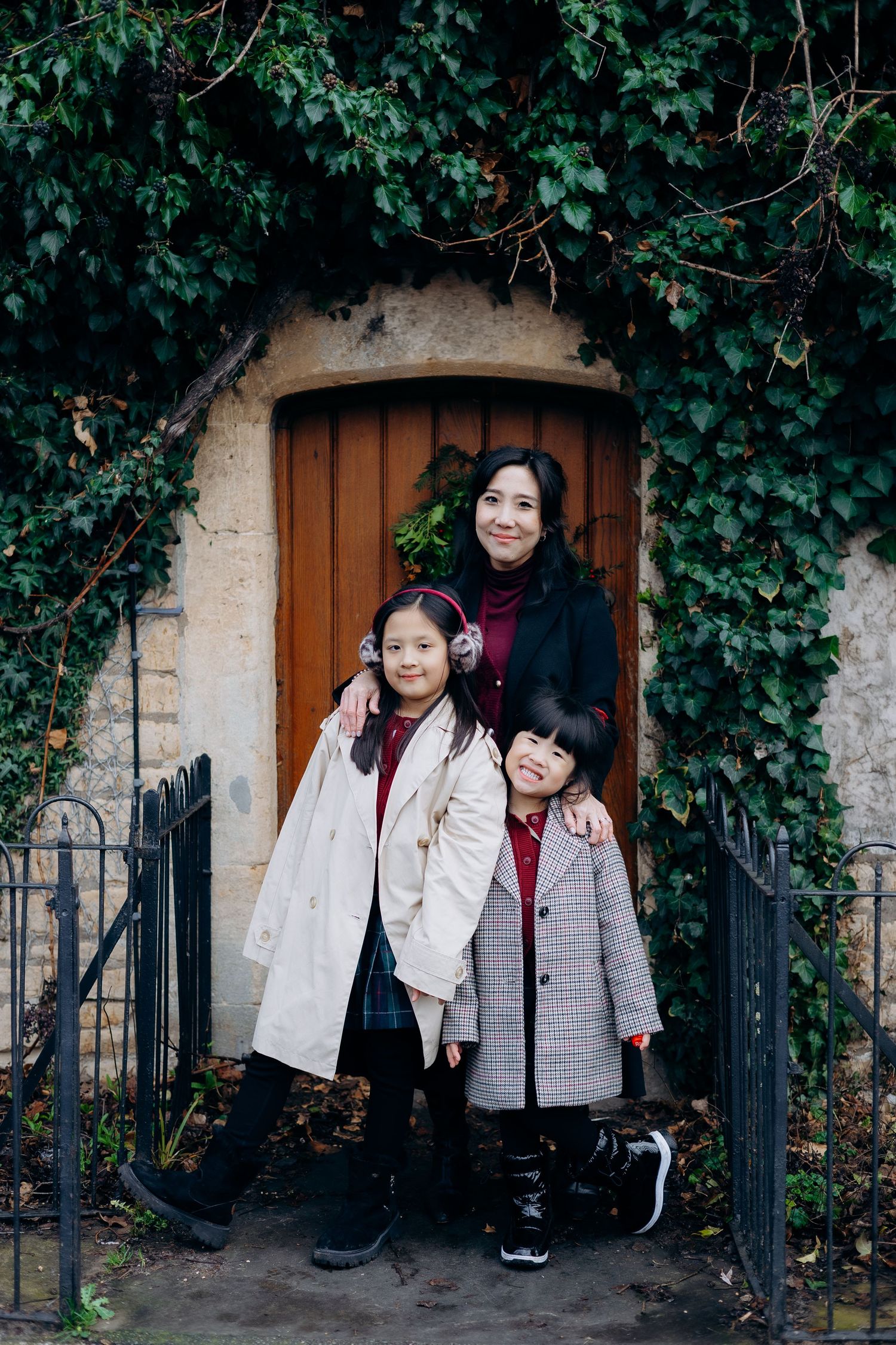 A series of photos showing people posing together in front of a wooden door surrounded by green ivy-covered walls.