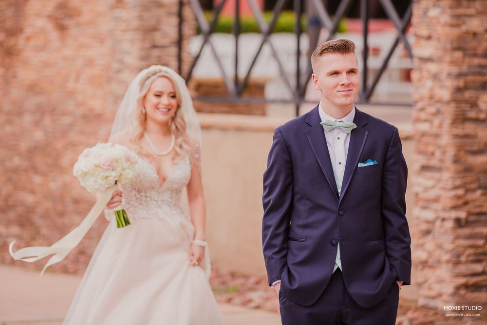 A bride and groom pose for wedding photos in front of a rustic brick wall on their special day.