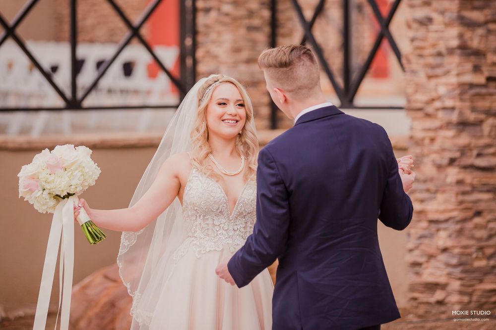 A couple in wedding attire dance together on a brick-lined patio during their celebration.