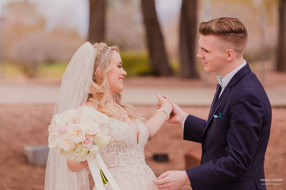A bride and groom share a joyful moment during their outdoor wedding ceremony in an autumn setting.