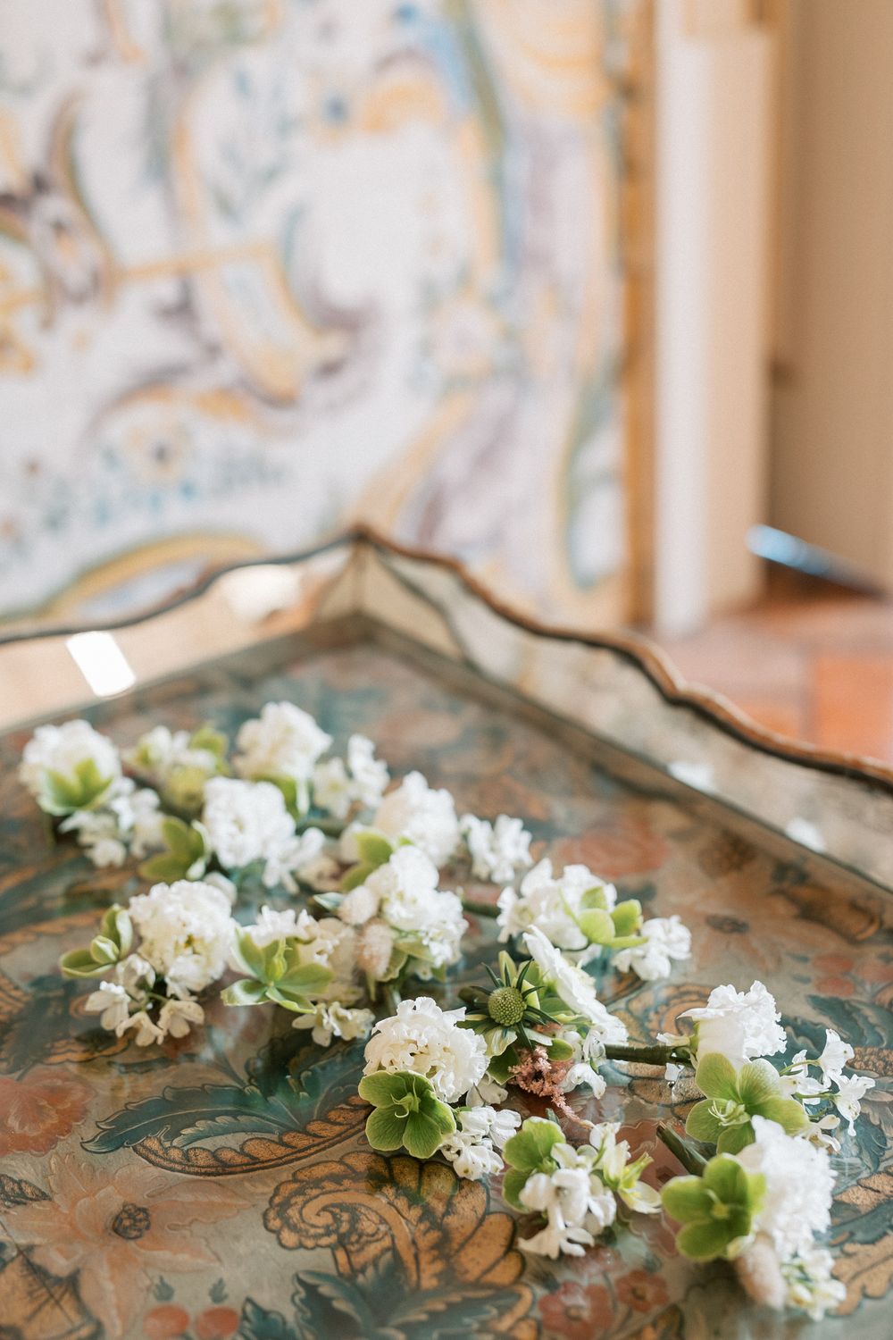 White and green wedding boutonnières styled on vintage tray at destination wedding in Portugal