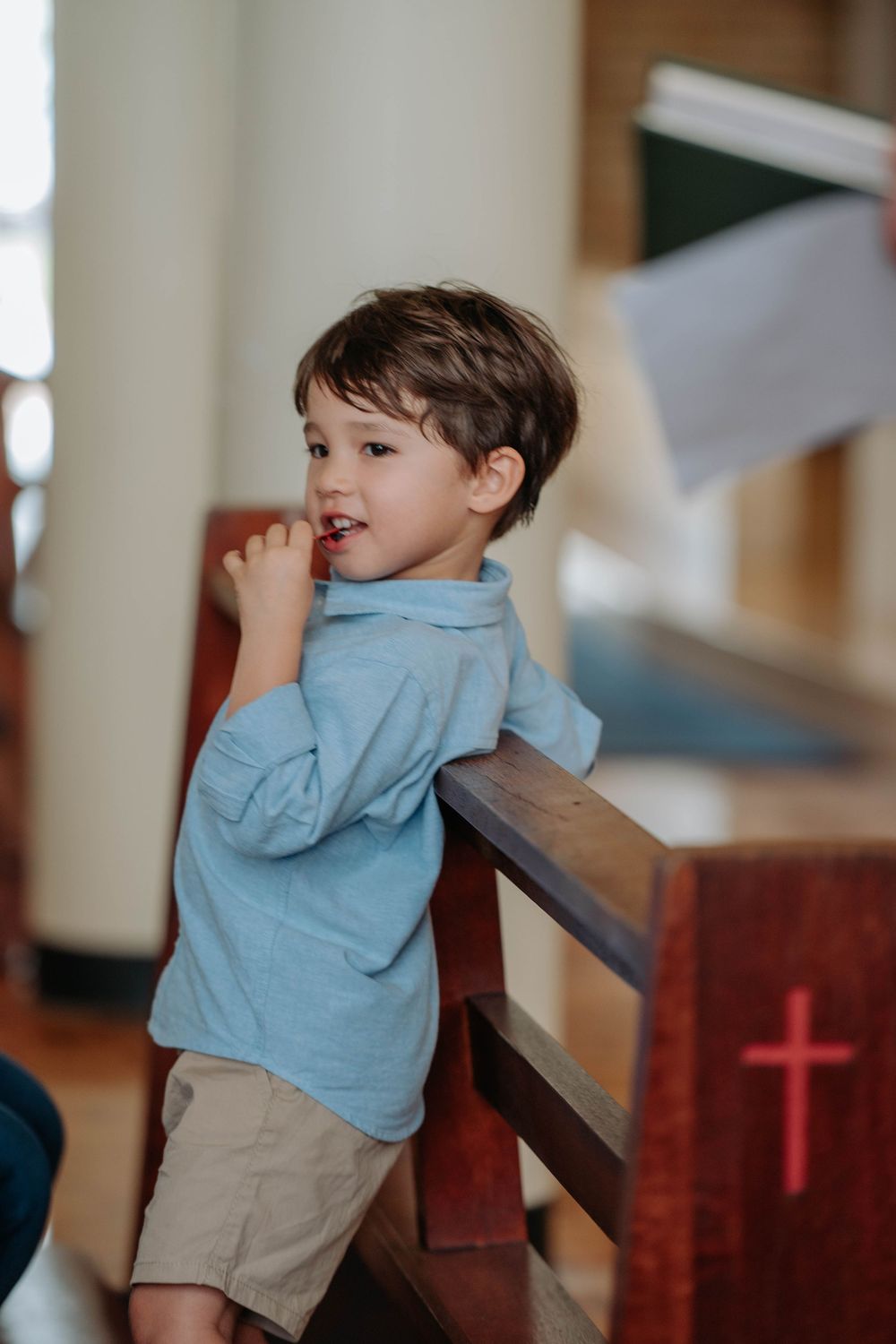 A child in a light blue shirt and khaki shorts leans against a wooden railing in a series of playful poses.