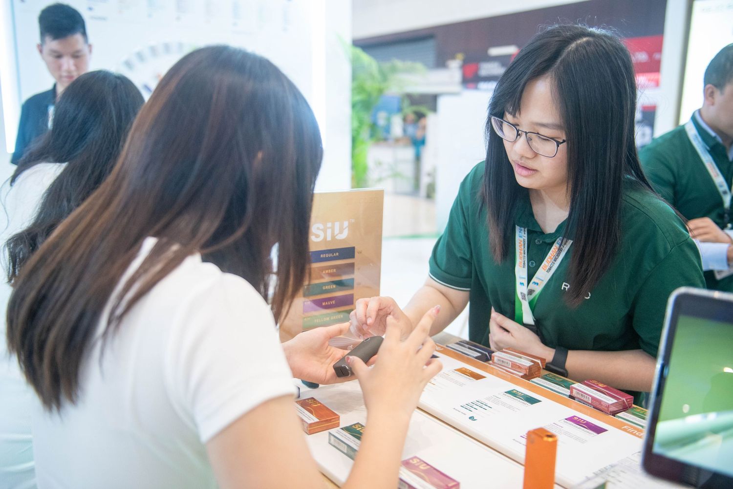 Students in school uniforms sit at a table having a discussion while looking at materials and devices.