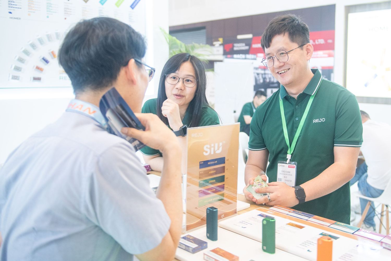 People interacting at a business booth or exhibition stand with product displays and beverages.