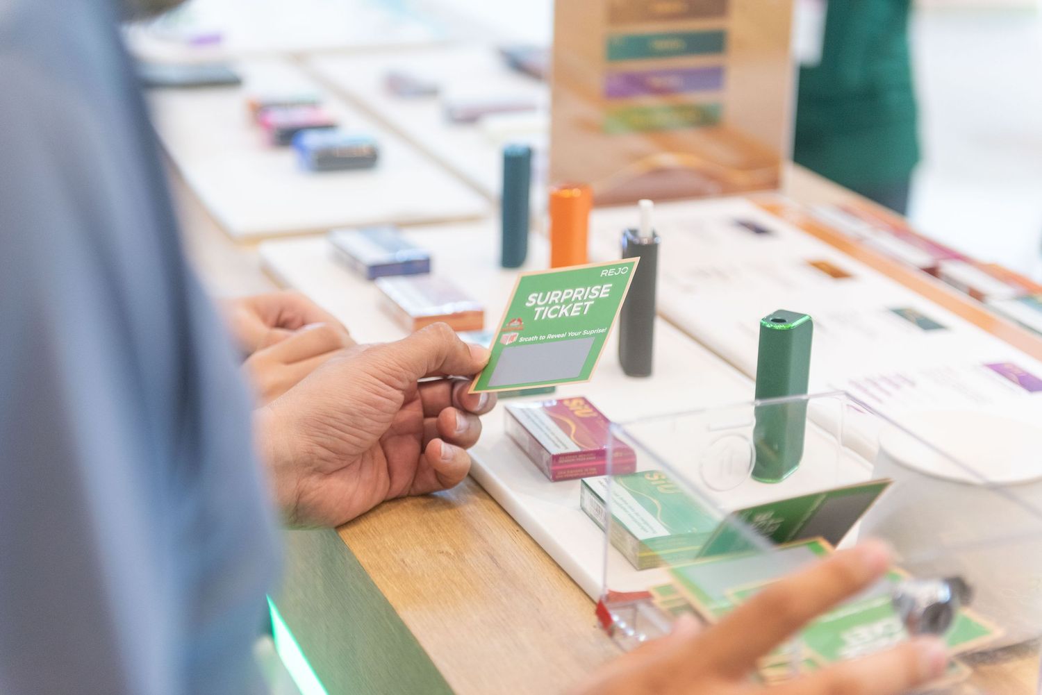 Someone holding a credit card while making a purchase at a retail counter with various products displayed.
