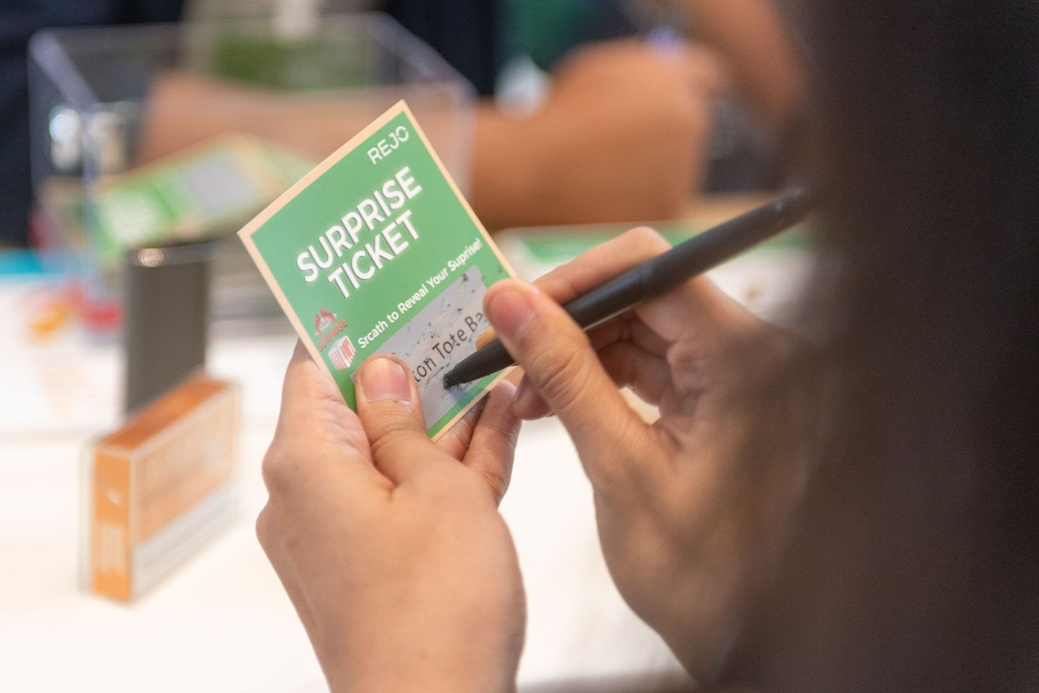 Close-up view of hands writing on small green cards or papers during a group activity.
