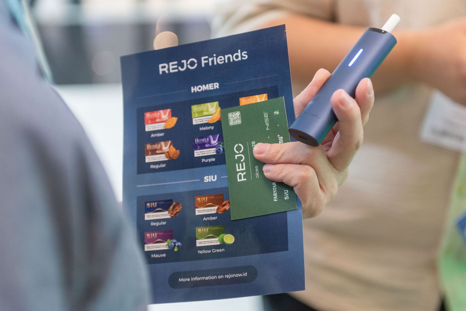 Close-up view of hands holding a navy blue REJO Friends loyalty card against a blurred background.