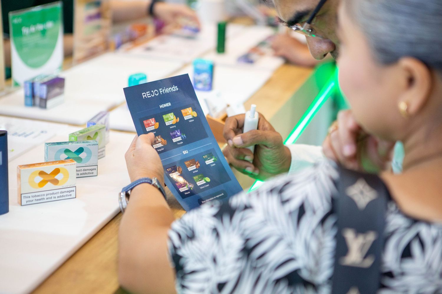 Someone in a feather-patterned top uses a tablet device while working with educational materials on a desk.