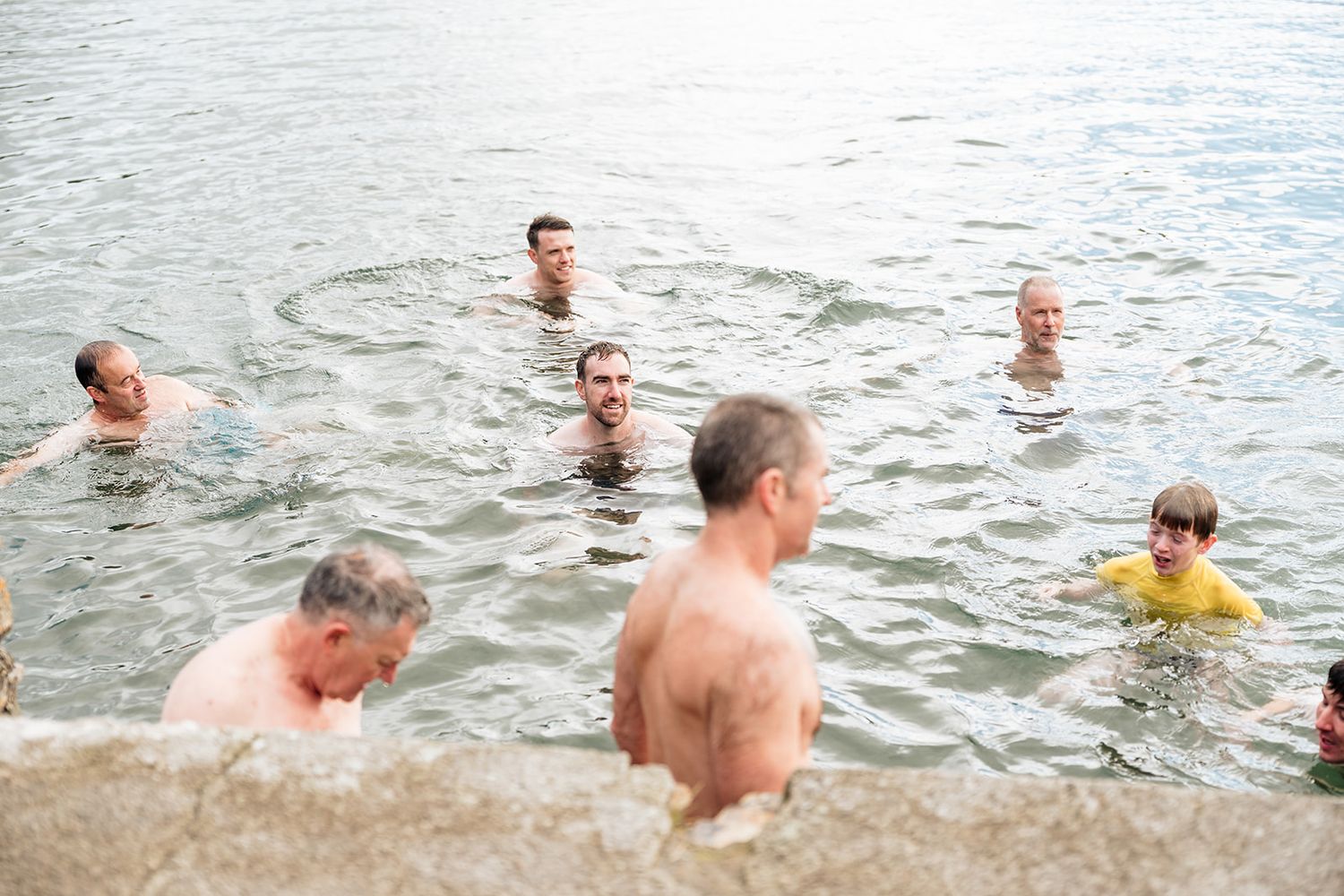 A group of swimmers enjoying the water at a lake or swimming hole on a summer day.
