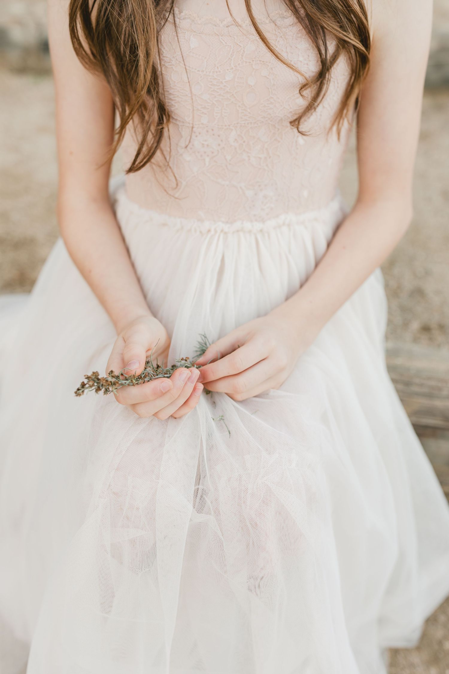 Close-up shots of hands wearing delicate rose gold rings against a light gray tulle dress background.