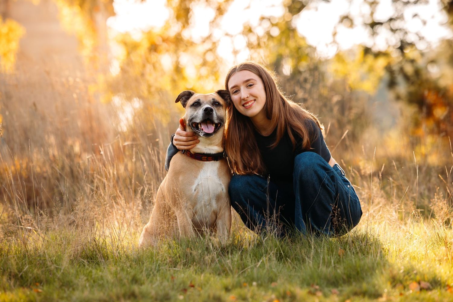 Dog and photographer relaxing together in grassy field during golden hour.