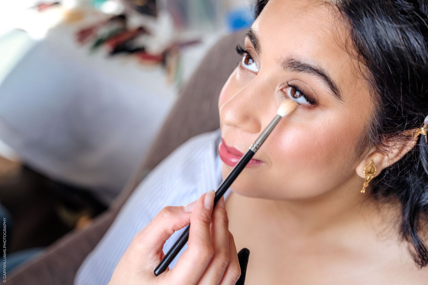 Professional makeup artist applying eyeshadow with a small brush during a beauty session.