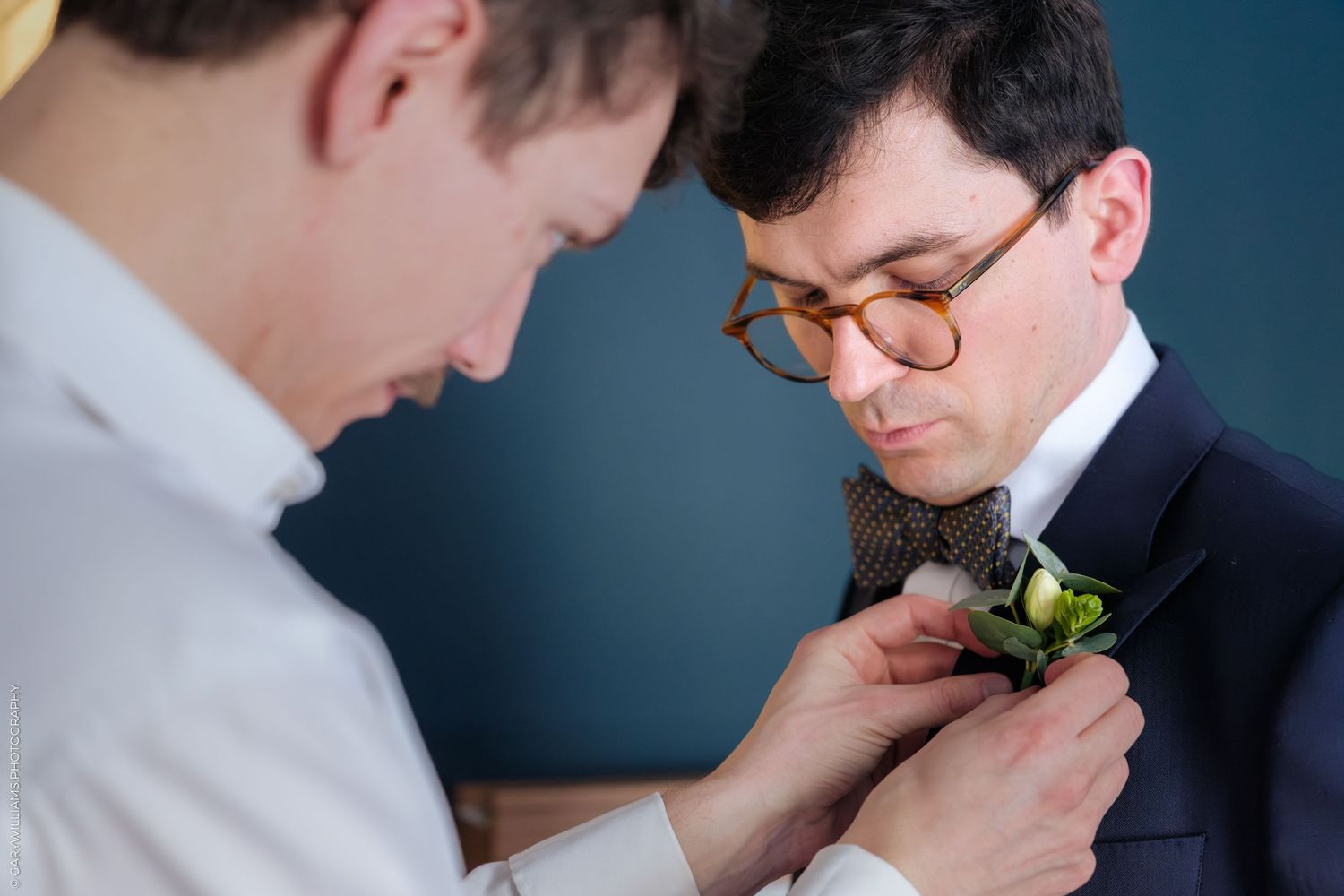 A close-up shot of a boutonniere being pinned to formal attire.