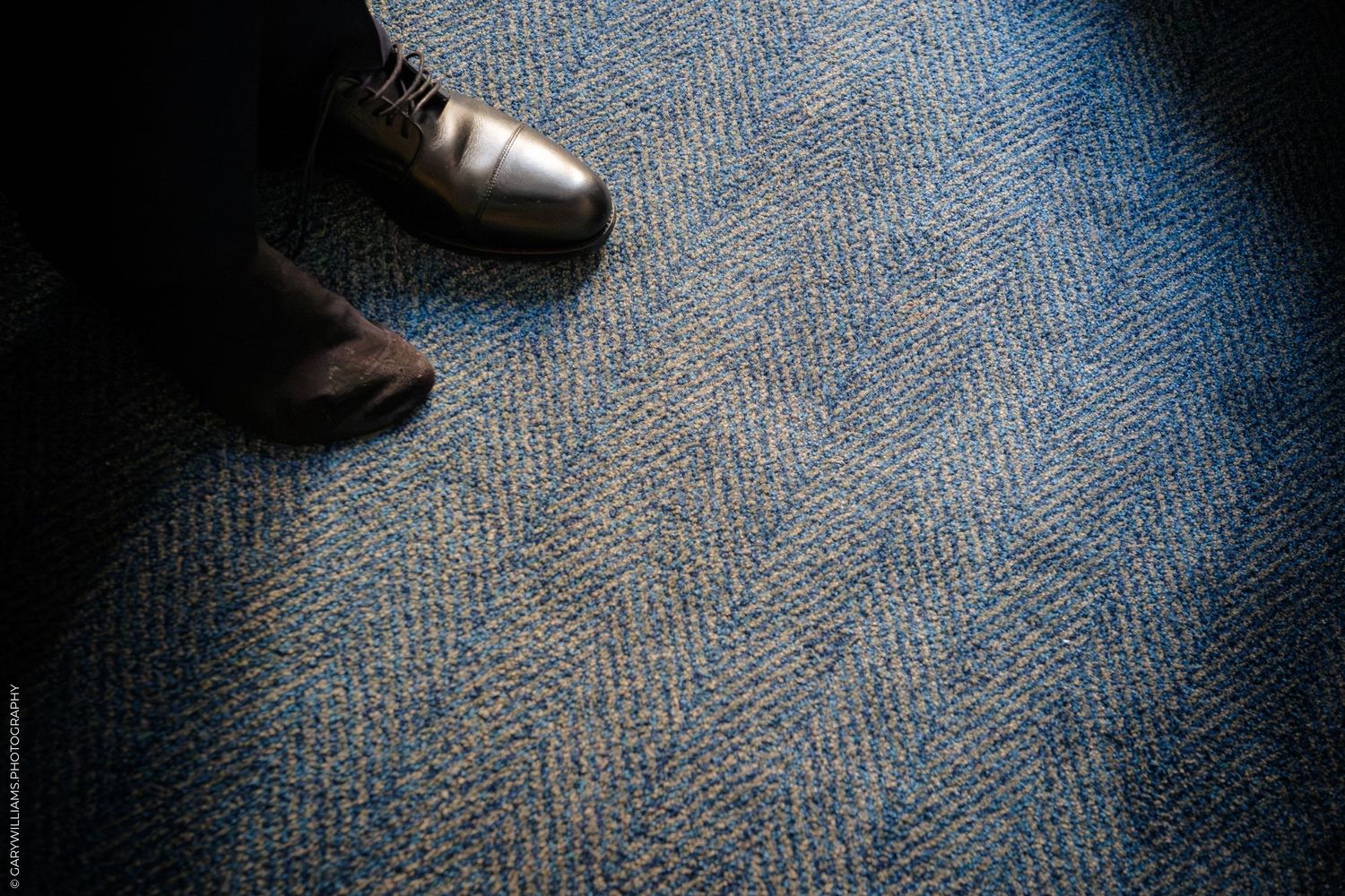 Wedding shoes and dress details on blue carpet showing elegant footwear and formal attire.