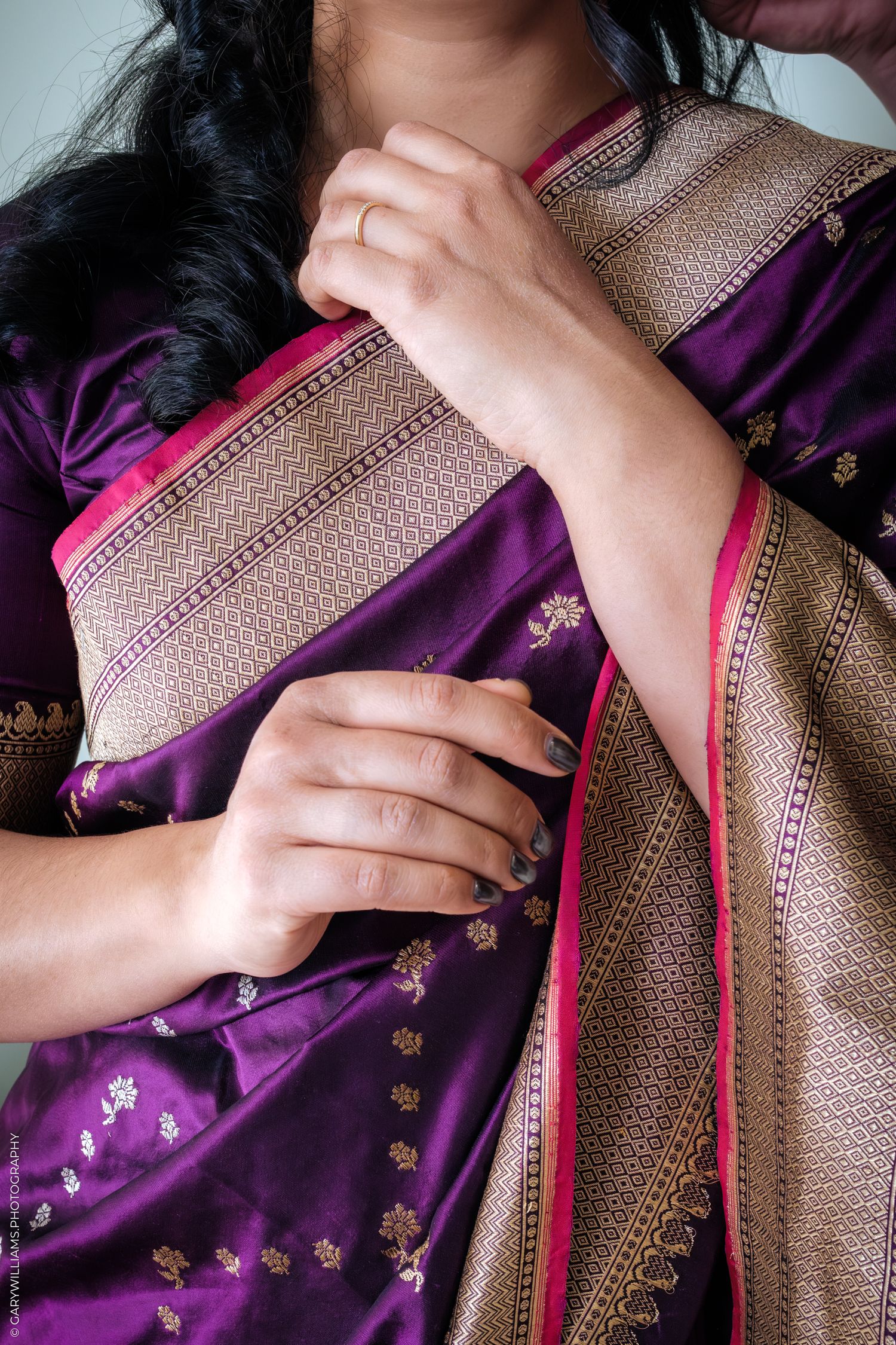 Close-up sequence showing hands adjusting a brown and purple sari with delicate embroidered details and pink trim.