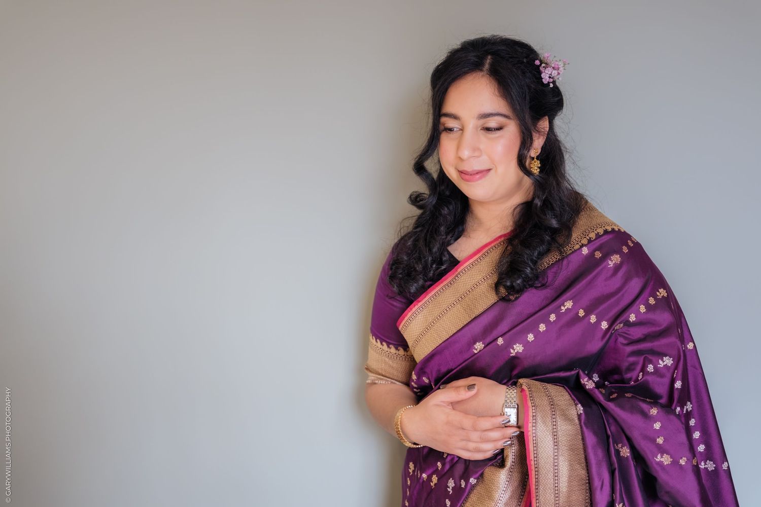 A person wearing a purple and gold traditional Indian sari with decorative embellishments.