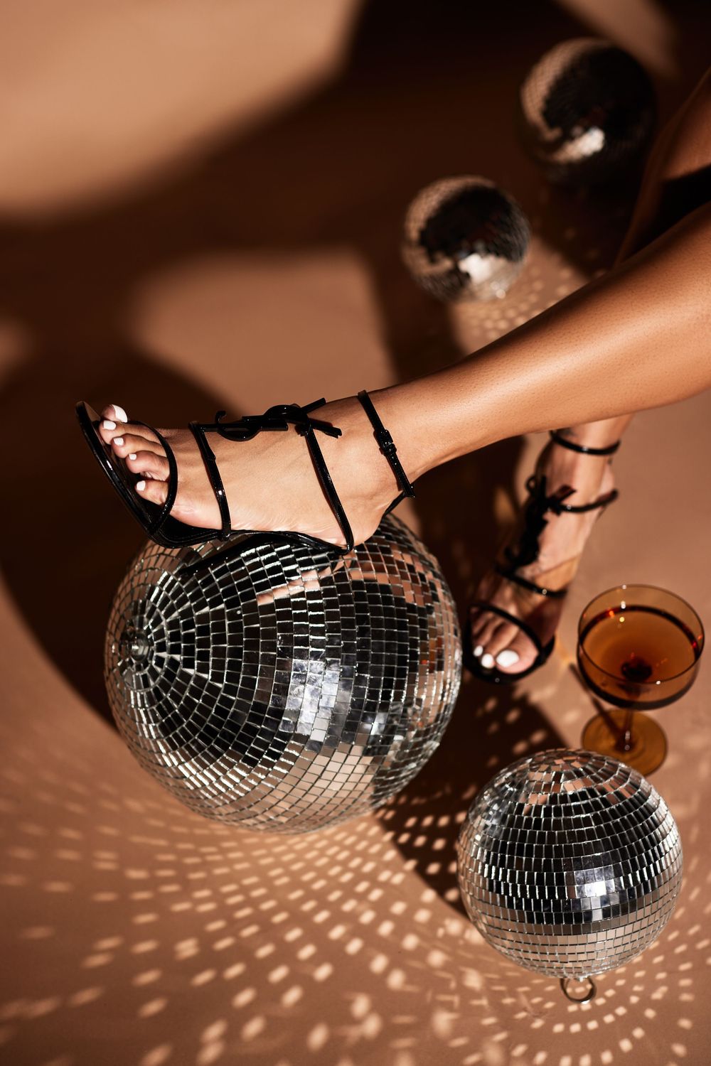Disco ball casts intricate light patterns in warm sepia tones against a dark background.