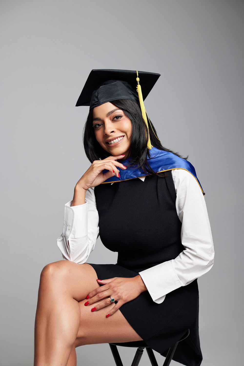 Graduation photoshoot featuring cap, gown, and white shirt in studio setting.