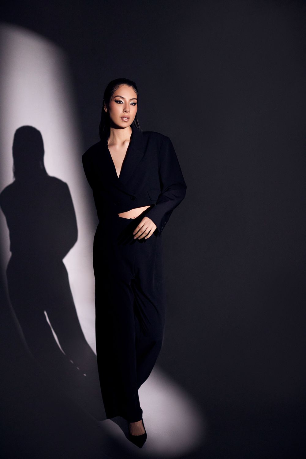 Artistic fashion series with strong shadow play against dark studio background.