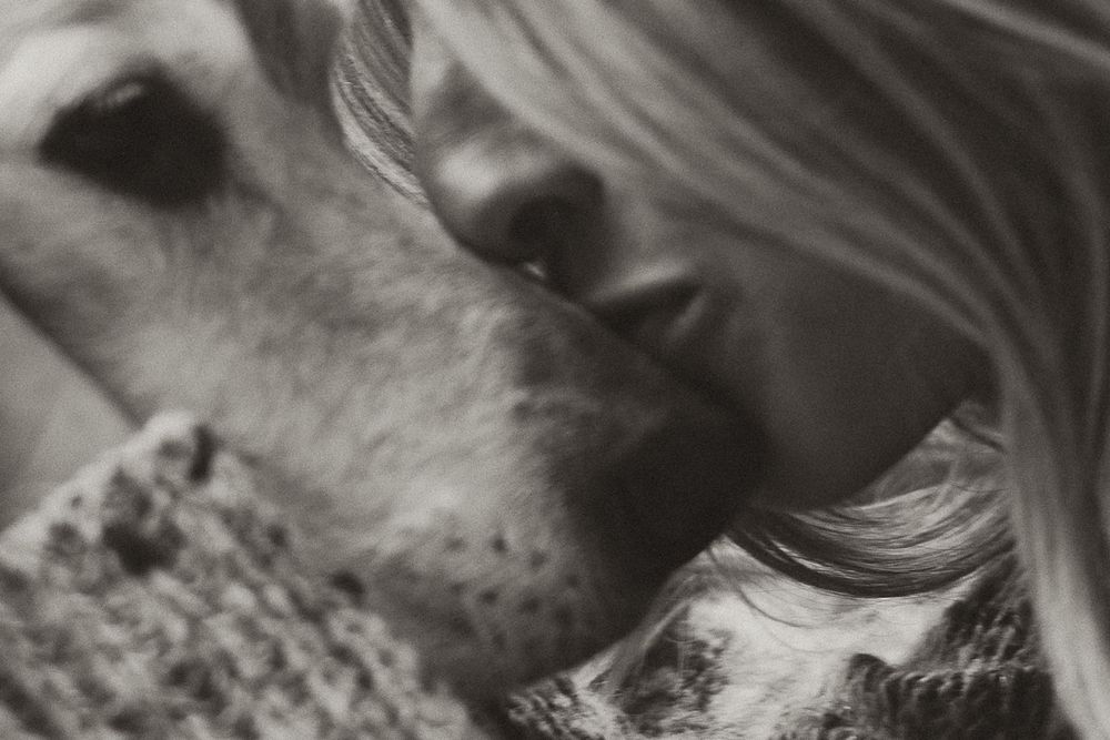 Intimate black and white close-up of person and dog sharing an affectionate moment.