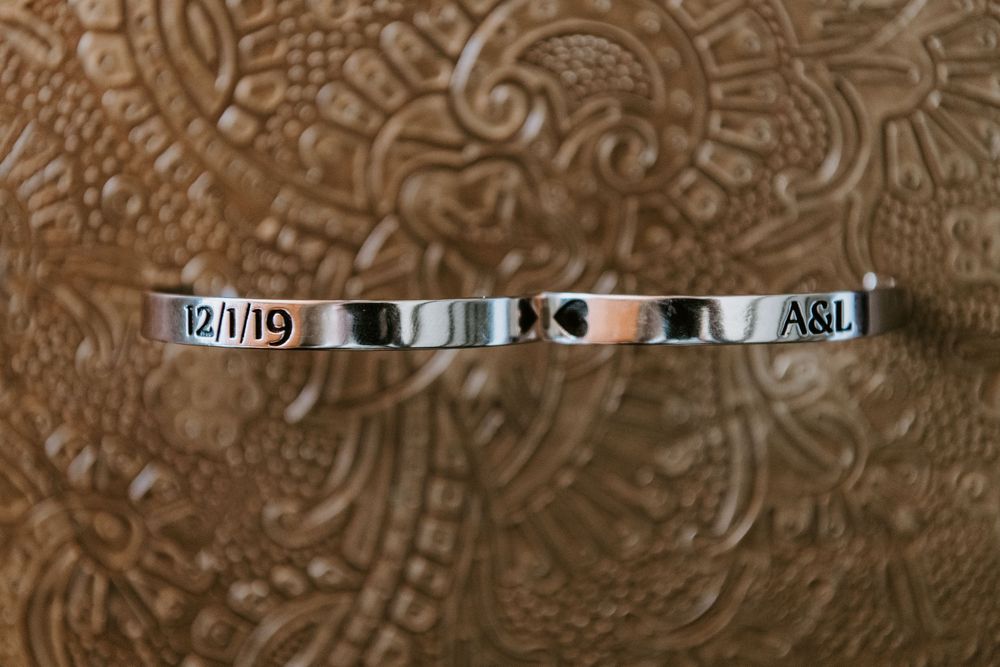 Silver cuff bracelet engraved with wedding date 12/1/19 and initials A&L on textured background.