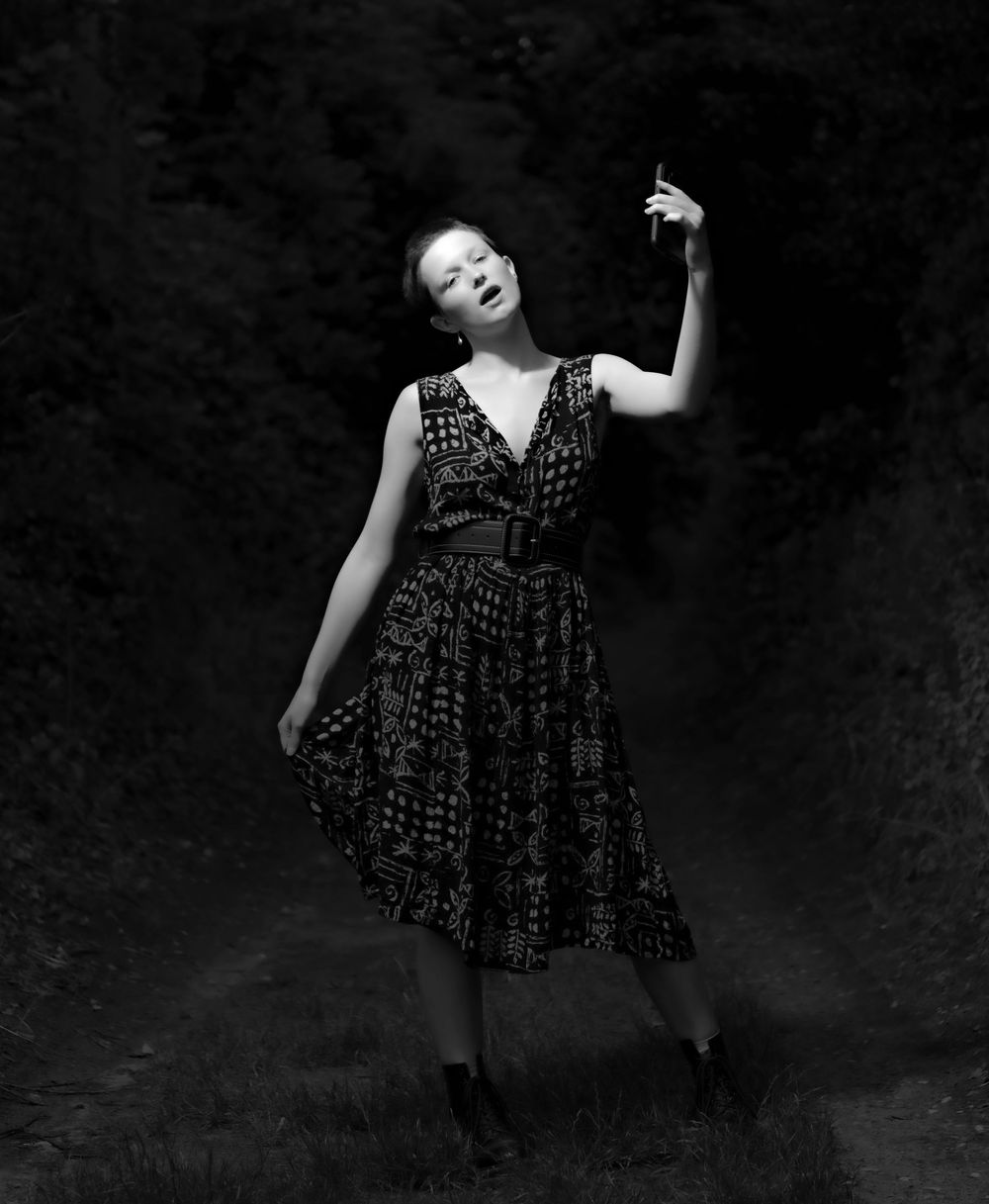 A figure in a patterned black dress poses dramatically against a dark background in a series of artistic shots.