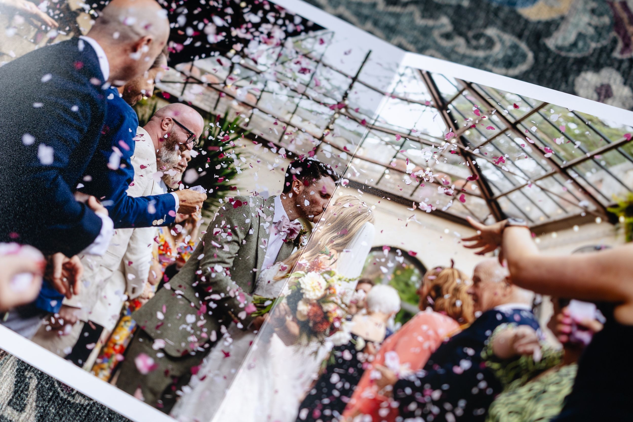 Wedding guests throw colorful confetti over celebrating couple during outdoor ceremony reception.