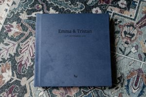 Navy blue wedding photo album cover with elegant text layout on textured background.