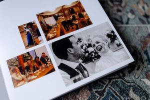 Wedding photo album pages displaying vintage-style photographs arranged on patterned fabric surface.