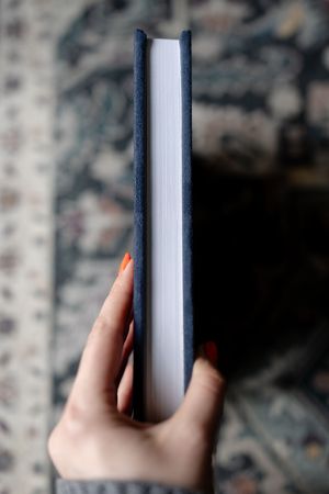 A series of photos showing hands holding a thick hardcover book from different angles against a blurred background.